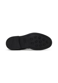 Suela de zapato de goma negra con un acabado liso, indentaciones redondas y un logo. La forma es plana con una ligera curvatura hacia la punta.