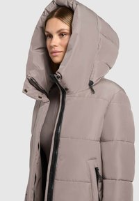 Pufferjack in licht taupe met een grote capuchon, rits- en drukknoopsluiting, zijzakken en een geborduurd ontwerp voor isolatie.