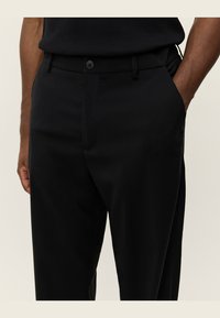 Black trousers with a smooth texture, featuring a button closure, side pockets, and a tailored fit. Made from lightweight fabric.