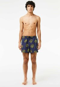 Bañadores de natación en color navy con cintura elástica, que presentan un patrón de logotipos en verde y amarillo. Fabricados con tela ligera y de secado rápido.