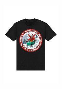 Camiseta de algodón negra con un gráfico de un esqueleto en un traje de Santa en un trineo, rodeado por un borde circular rojo con texto en blanco.