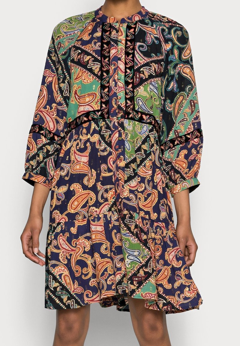 Vestido de manga larga en azul marino oscuro con un colorido patrón de paisley, que presenta un escote con volantes y detalles de botones en el frente. Diseño de tela fluida.