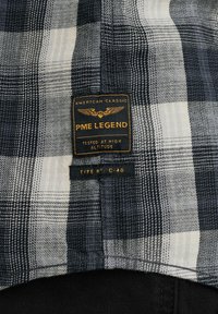 Geruite overhemd in een mix van marineblauw, zwart en wit; voorzien van PME Legend-label met vleugels en "GETEST OP HOOGTE."