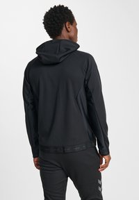 Zwarte sporthoodie van zachte, gestructureerde stof. Voorzien van een capuchon met trekkoord en een slank ontwerp met contrasterende paneeldetails.