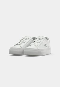 Witte leren sneakers met een gestructureerd oppervlak, ronde neus, platte rubberen zool en veters. Voorzien van een subtiele logo aan de zijkant.