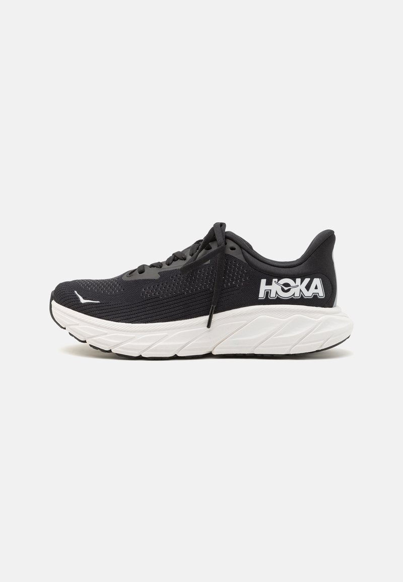 Black running shoe with a mesh upper, white midsole, and textured black outsole. Features logo on the side and flat laces.