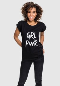 Sort bomulds T-shirt med hvid tekst "GRL PWR" i en fed, spraymalet stil. T-shirten har korte ærmer og en afslappet pasform.