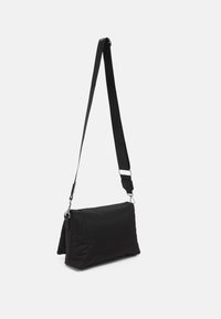 Black nylon crossbody bag with a flat rectangular shape, an adjustable strap, and subtle stitching detail. Smooth texture, minimalistic design.