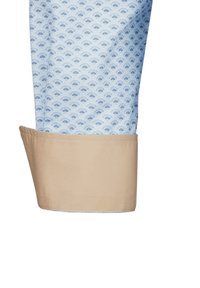Himmelblaues Hemdmotiv mit Fächerdesign, kombiniert mit einem kontrastierenden beige Farbton am Saum. Der Stoff hat eine glatte Textur und wirkt leicht.