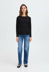 Svart langermet topp, blå rettbuksjeans og svarte leiligheter. Glatt stoff med avslappet passform og rund halslinje. Enkelt design, uten mønster.