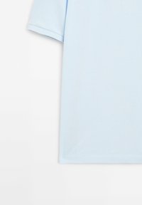 Polo bleu clair à manches courtes en tissu texturé, présenté de la taille jusqu'au milieu de la manche sur fond blanc.