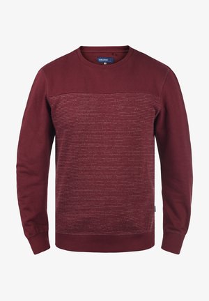 Tamsiai raudonas megztinis su tekstūruota dalimi, apvaliu kaklu ir rausvomis rankovėmis. Papuoštas horizontaliomis linijų raštais šviesesnėje atspalvyje.