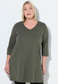 Olivgrön tunika med V-hals, trekvartslånga ärmar och avslappnad passform, tillverkad av mjukt tyg med en slät textur.