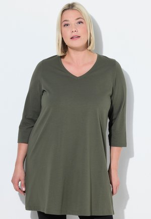 Túnica verde oliva con escote en V, mangas tres cuartos y un corte relajado, hecha de tejido suave con una textura lisa.