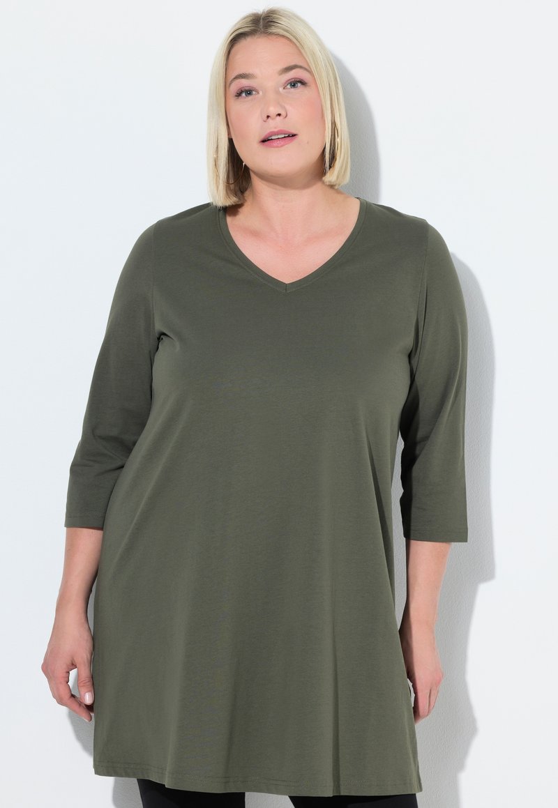 Olivgrön tunika med V-hals, trekvartslånga ärmar och avslappnad passform, tillverkad av mjukt tyg med en slät textur.