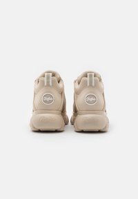 Beiga sneakers med en strukturerad ovandel, vadderad krage och gummisula. Har en logotyppatch och en dragflik för enkel påtagning.