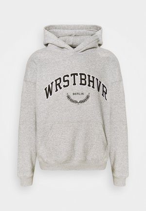Sudadera con capucha gris claro con texto negro "WRSTBHVR" y "BERLIN" sobre un pequeño diseño de corona de laurel en la parte delantera.