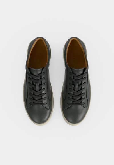 Ζευγάρι μαύρα δερμάτινα αθλητικά παπούτσια χαμηλού τύπου με μαύρα κορδόνια και μπεζ σόλες, απεικονισμένα από πάνω σε λευκό φόντο.