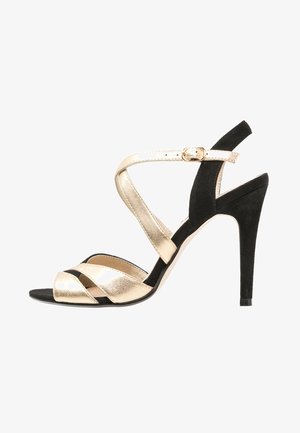 Sandale à talon haut noire et dorée avec des brides croisées en cuir métallique et en daim, dotée d'une boucle à la cheville et d'un design à bout pointu.