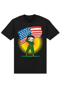 Schwarzes T-Shirt mit einer Cartoonfigur in grüner Kleidung, die salutiert, vor einer wehenden amerikanischen Flagge und einem gelben Burst im Hintergrund.