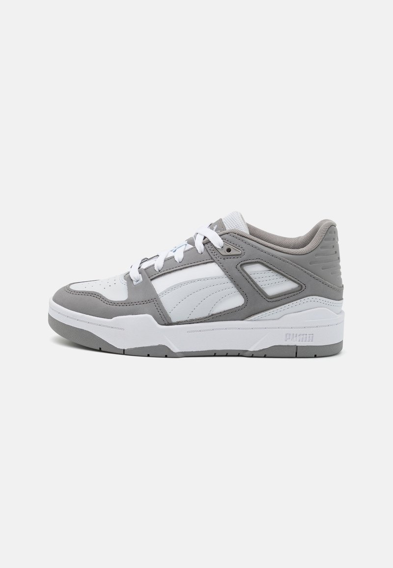 Sneaker bianco e grigio con tomaia in pelle e mesh, suola in gomma, colletto imbottito e accenti in contrasto discreti. Presenta un marchio prominente.