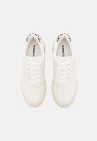 Baskets en cuir blanc avec un bout rond, des détails perforés et des lacets plats. Le talon présente une accent en imprimé léopard noir et blanc.