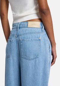Lichtblauwe denim jeans met een relaxed fit, voorzien van twee achterzakken, contrasterende stiksels en een tan leren merkpatch op de taille.
