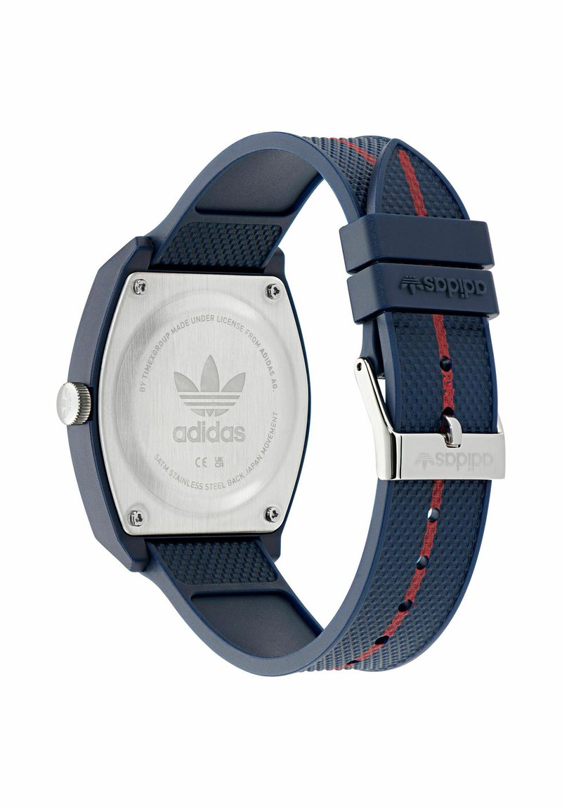 Adidas-Uhr mit marineblauem, strukturiertem Armband, rotem Mittelstreifen, Edelstahlrückseite und silberner Schnalle mit eingraviertem Adidas-Logo.
