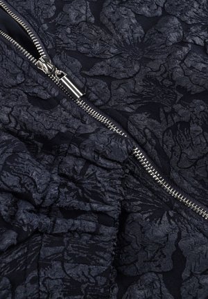 Gestructureerde donkere marineblauwe stof met een bloemenpatroon, voorzien van een gepolijste zilveren rits en geraffineerde details langs de naad.