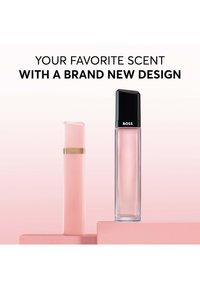 Deux flacons de parfum roses présentés sur des blocs roses, l'un avec un bouchon noir étiqueté "BOSS", mettant en avant un nouveau design produit.