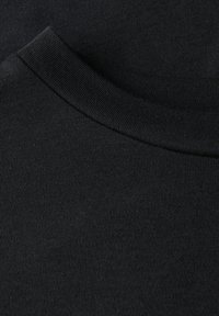 Primo piano di un colletto di una T-shirt nera in cotone con collo a girocollo a costine e trama a maglia visibile.