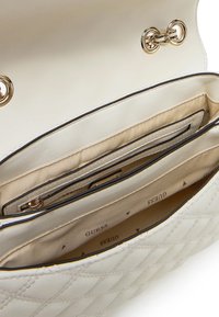 Borsa a tracolla trapuntata color crema con dettagli in oro, un ampio interno con scomparti e una morbida fodera interna contrassegnata "Guess".