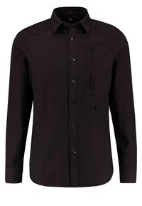 Chemise noire à manches longues avec boutons, col et poche poitrine zippée sur le côté gauche.