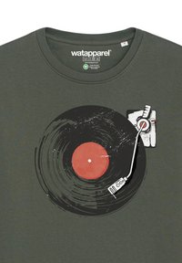 Donkergroene t-shirt met een afbeelding van een zwarte vinylplaat met een rode kern en een gestileerde draaitafelarm in het wit.