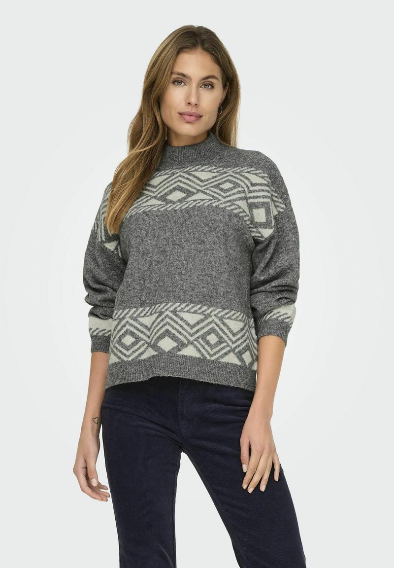 Pull en tricot gris avec un col haut, présentant un motif géométrique crème sur la poitrine et les manches, et des poignets côtelés.