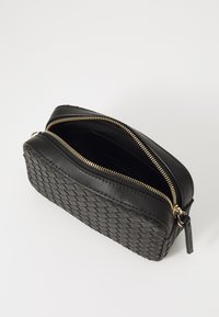 Borsa in pelle intrecciata nera con chiusura a zip, caratterizzata da hardware color oro e un interno aperto. Forma compatta e rettangolare.