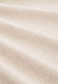 Helle beige Stoff mit einer weichen, strukturierten Oberfläche, die ein dezentes Webmuster und sanfte Falten zeigt für ein glattes Erscheinungsbild.