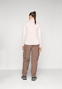 Long-sleeve, light pink top paired with brown cargo pants; top features a fitted design, pants have cargo pockets and a loose fit.