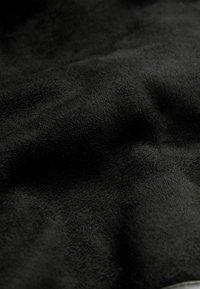 Zwart suède stof met een zachte, gestructureerde oppervlakte, gekenmerkt door subtiele schaduwvariaties en een licht matte afwerking.