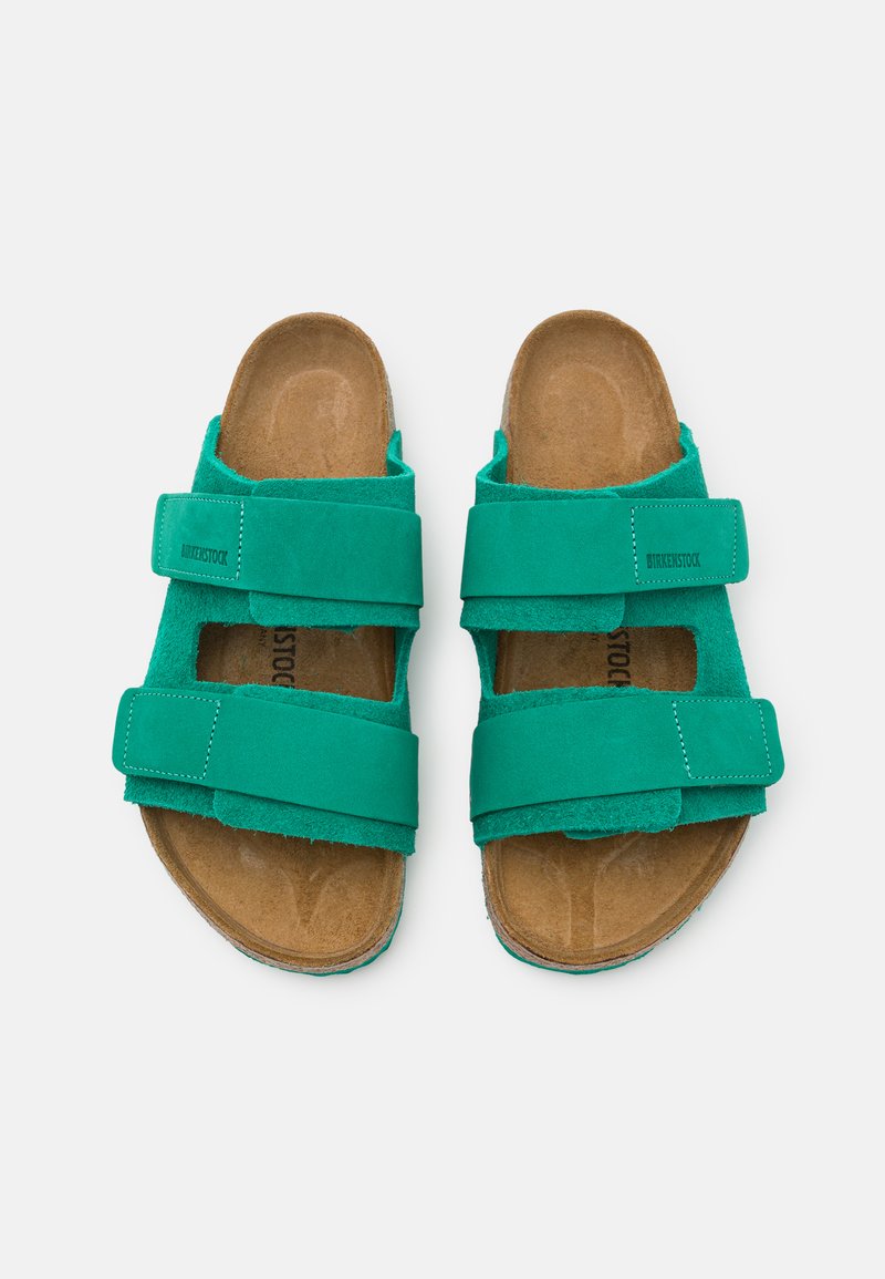 Grüne Wildledersandalen mit zwei verstellbaren Riemen, einem konturierten Korkfußbett und einem strukturierten Innenfutter. Mit Birkenstock-Branding.