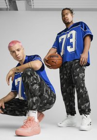 Blå mesh-trøje med hvidt nummer 73, sorte mønstrede bukser med basketball-motiver, lyserøde og hvide sko, basketball i hånden.