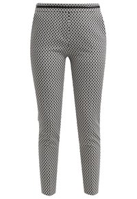 Pantalon noir et blanc à coupe slim avec une taille élastique présentant un motif géométrique répétitif.