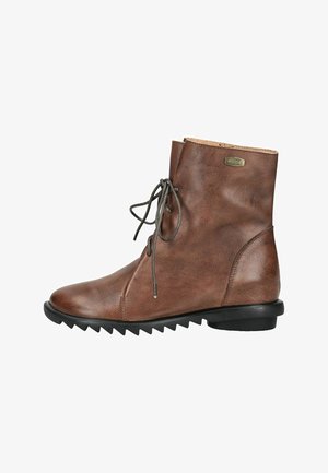 Brauner Lederknöchelstiefel mit schwarzer Schnürung vorne und schwarzer Gummisohle mit tiefem Zickzack-Profil, Seitenansicht.