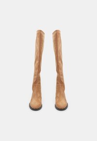 Botas de ante en color beige hasta la rodilla, con una textura suave, punta redondeada y un diseño minimalista. Cuentan con una suela negra plana.