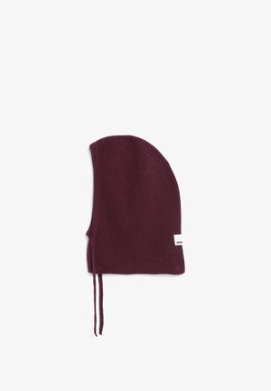 Bordeaux ribgebreide muts met strikjes onder de kin en een klein wit label aan de zijkant tegen een witte achtergrond.