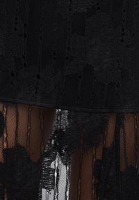 Μαύρο φόρεμα από δαντέλα με λουλουδένια μοτίβα, ημιδιάφανα στρώματα από δίχτυ και στενό πάνω μέρος με φαρδιά σιλουέτα.