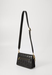 Schwarze, gesteppte Lederhandtasche mit einer reißverschlussseitigen Tasche, verstellbarem Tragegurt und goldfarbenen Hardware-Akzenten. Kompakte, rechteckige Form.