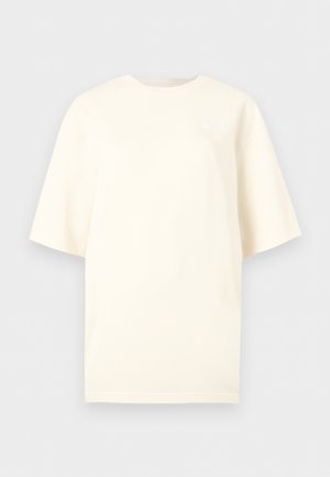 Prosta, oversize'owa, krótkorękawowa koszulka w kolorze kremowym, z okrągłym dekoltem i minimalnym, widocznym logo na górze klatki piersiowej.