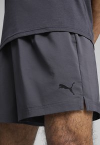 Γκρι αθλητικό σορτς με άνετη εφαρμογή, διαθέτει μαύρο λογότυπο Puma στο πλάι και διακριτή υφή. Διάτρητες πλευρές για ευκολία στην κίνηση.