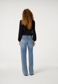 Weite blaue Jeans aus Denim mit einer hellen Waschung, mittelhoher Taille, Gesäßtaschen und kontrastierenden Nähten.